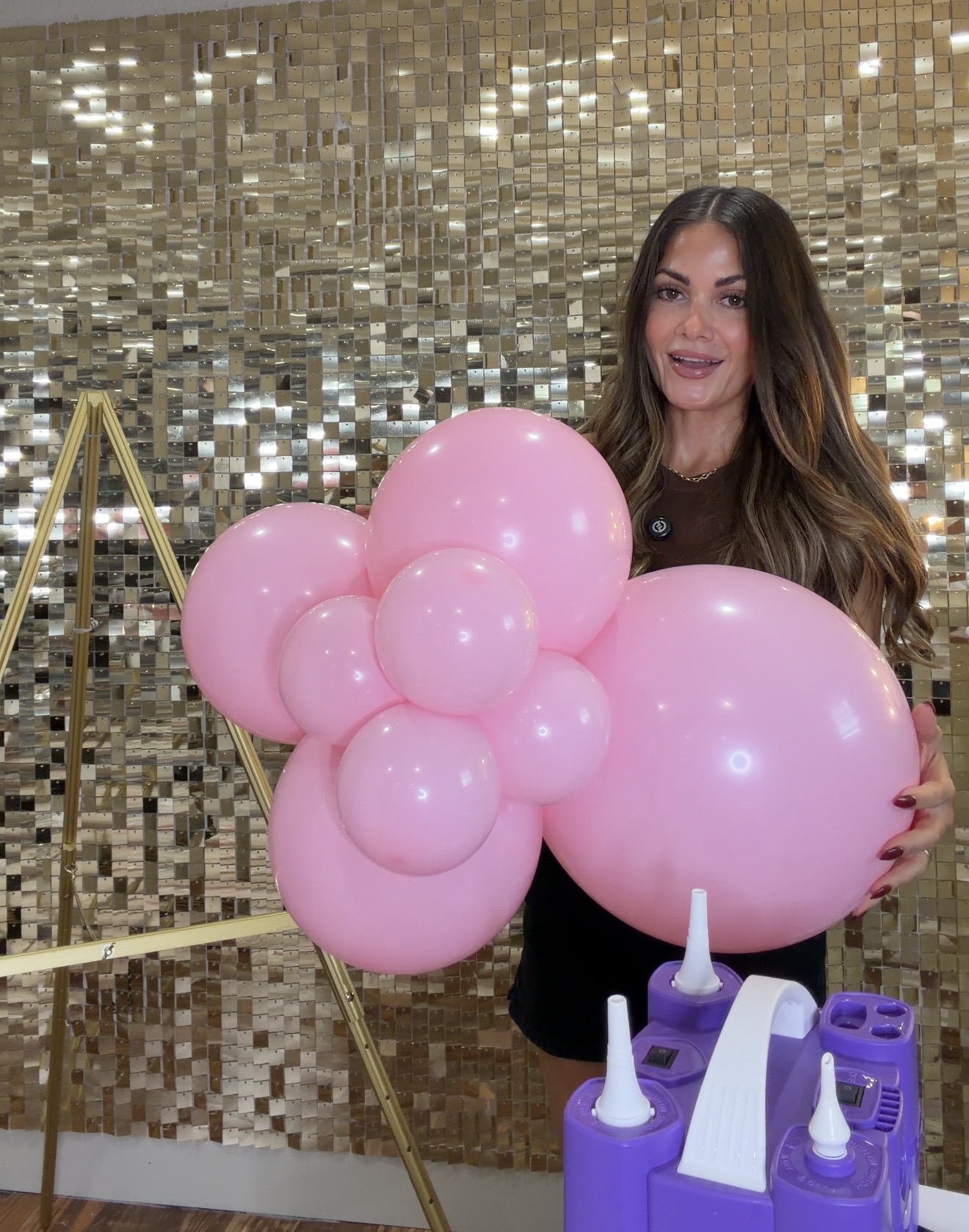 Aline demonstrating a pink balloon cluster with a mix of balloon sizes